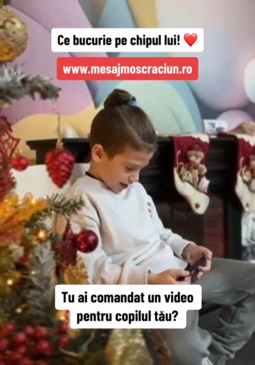 Un băiat zâmbește lângă bradul de Crăciun în timp ce își vede videoclipul