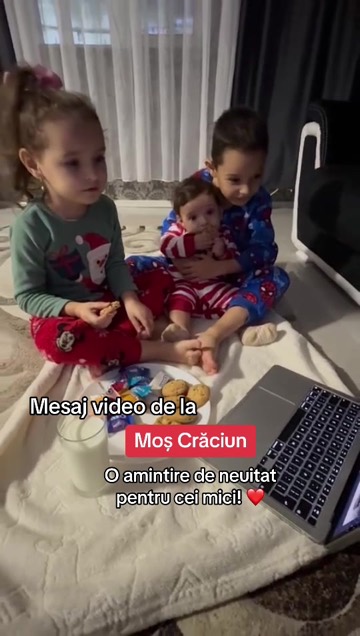 Trei frați în pijamale de Crăciun urmăresc pe laptop mesajul de la Moș Crăciun